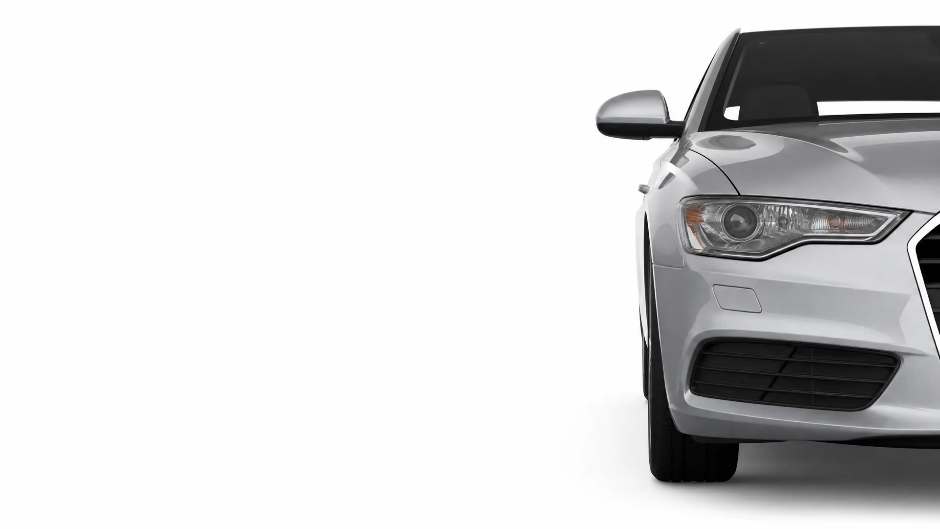 Front left portion of a silver sedan, showing the headlight, side mirror, wheel and lower grille, against a plain white background.