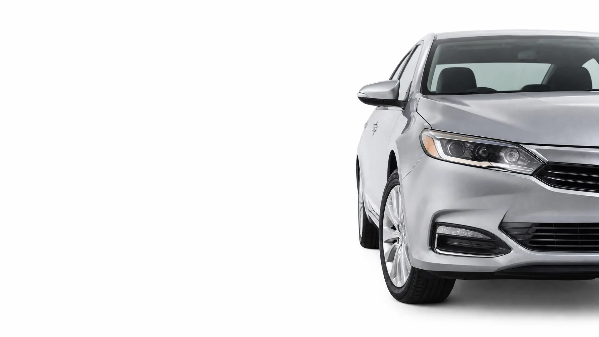 Front half of a silver four-door sedan photographed against a plain white background, angled toward the right side of the frame.