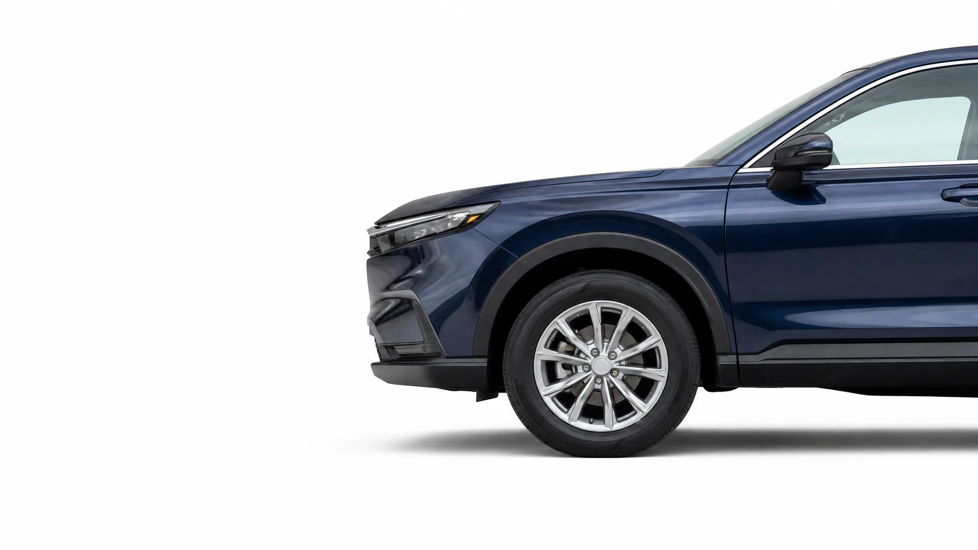 Partial side view of the front half of a dark blue SUV with alloy wheels, photographed against a plain white background.