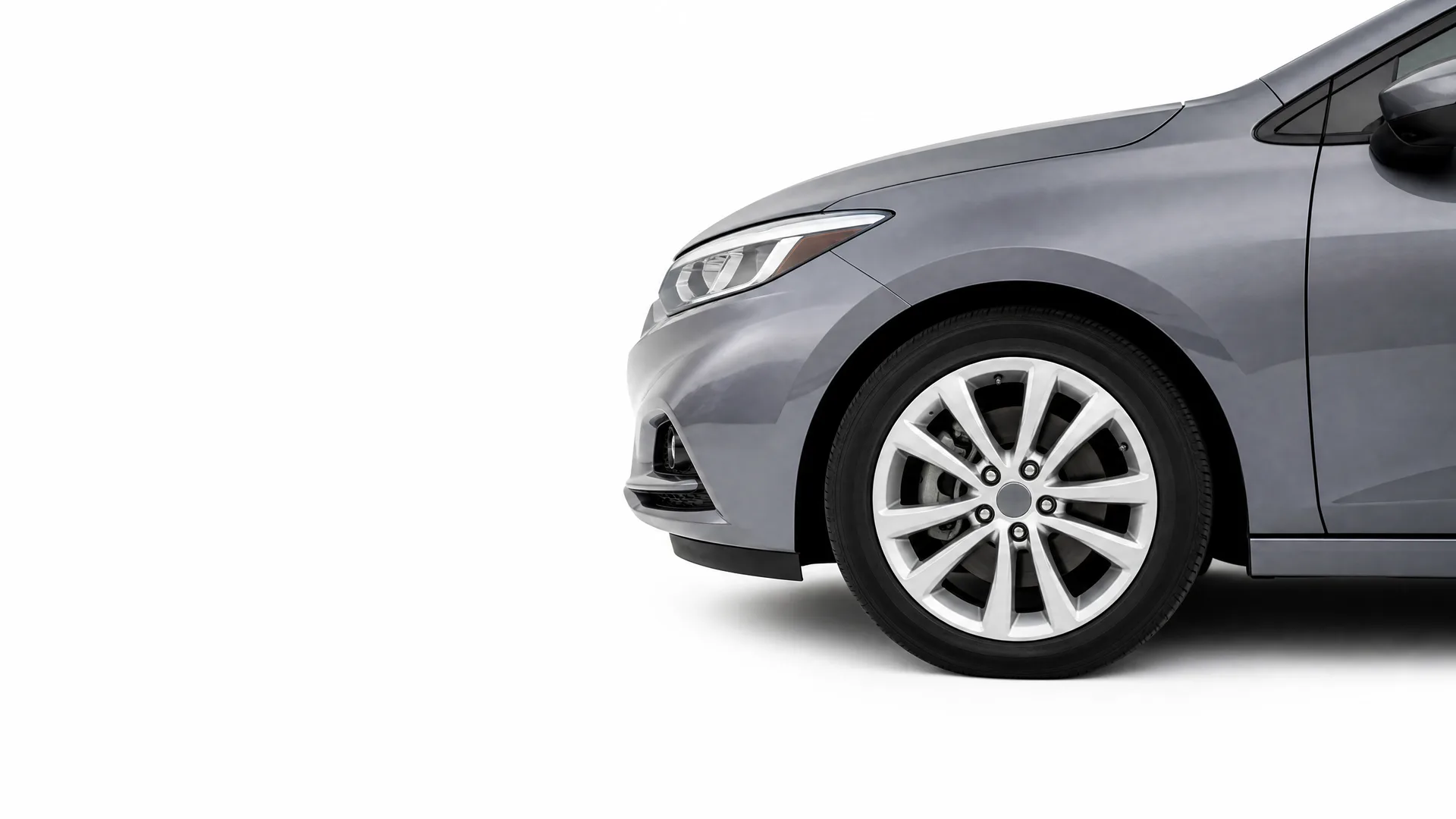 Front portion of a gray sedan, showing the headlight, bumper, front wheel with multi-spoke alloy rim, and side mirror, against a plain white background.