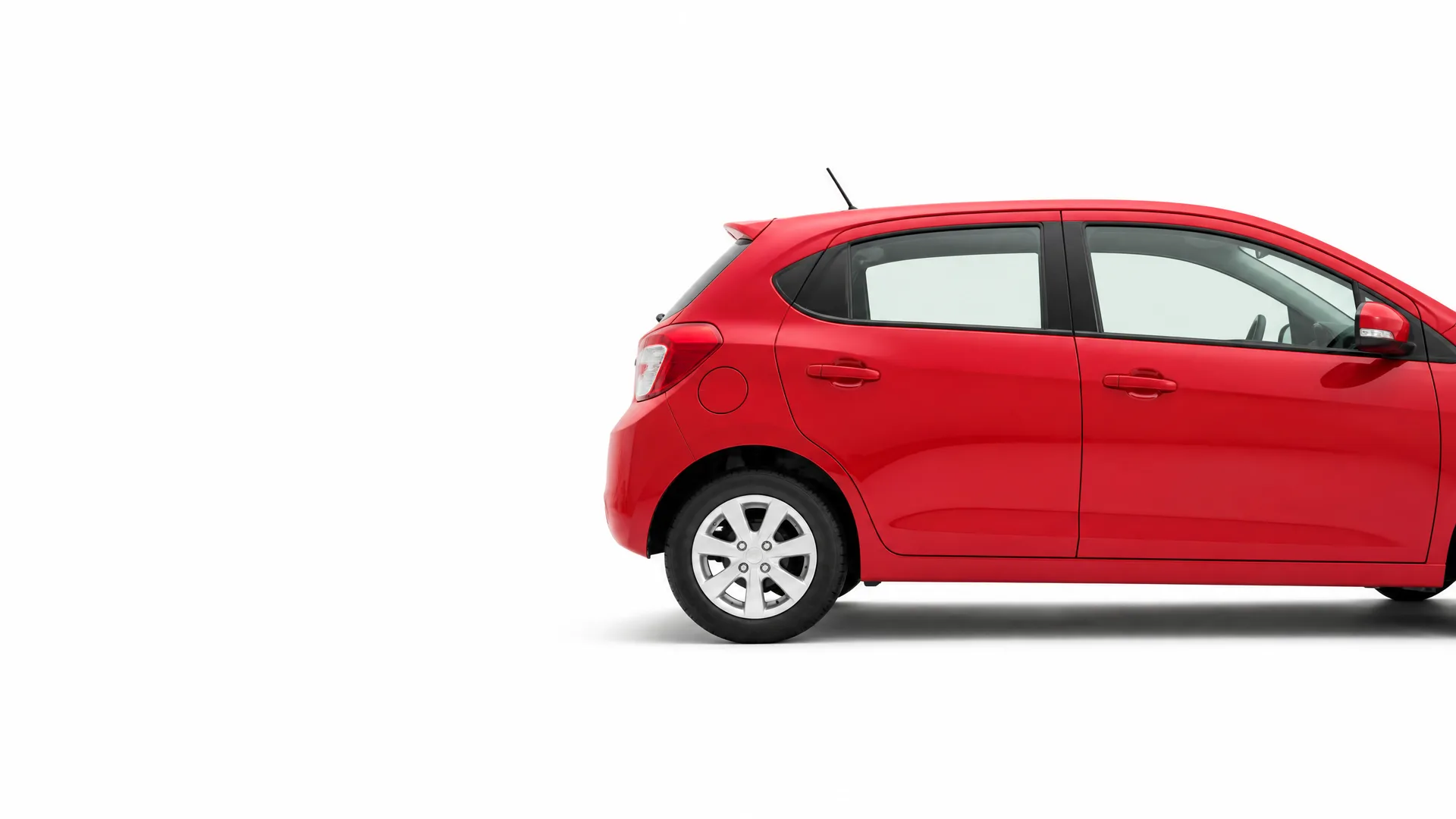 Partial side view of a red five-door hatchback car, showing the rear and middle sections, against a plain white background with a soft shadow beneath.