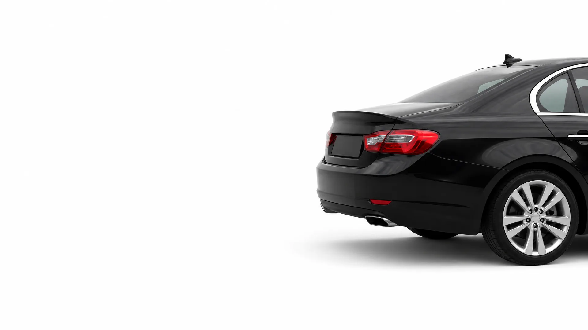 Rear three-quarter view of a black sedan with a trunk spoiler and red taillights on a plain white background.