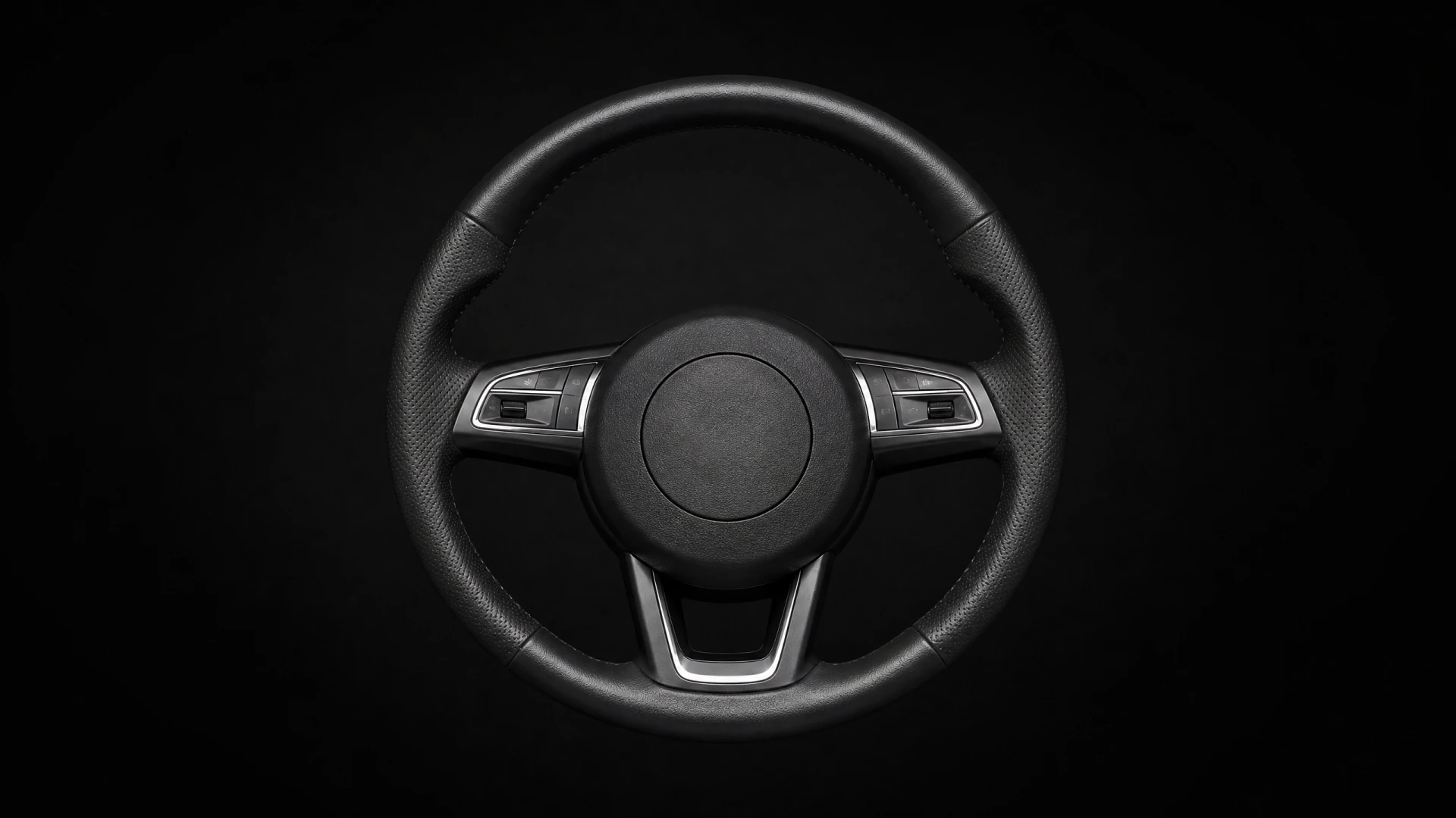 A black leather three-spoke car steering wheel with silver trim accents and mounted control buttons, shown against a dark background.