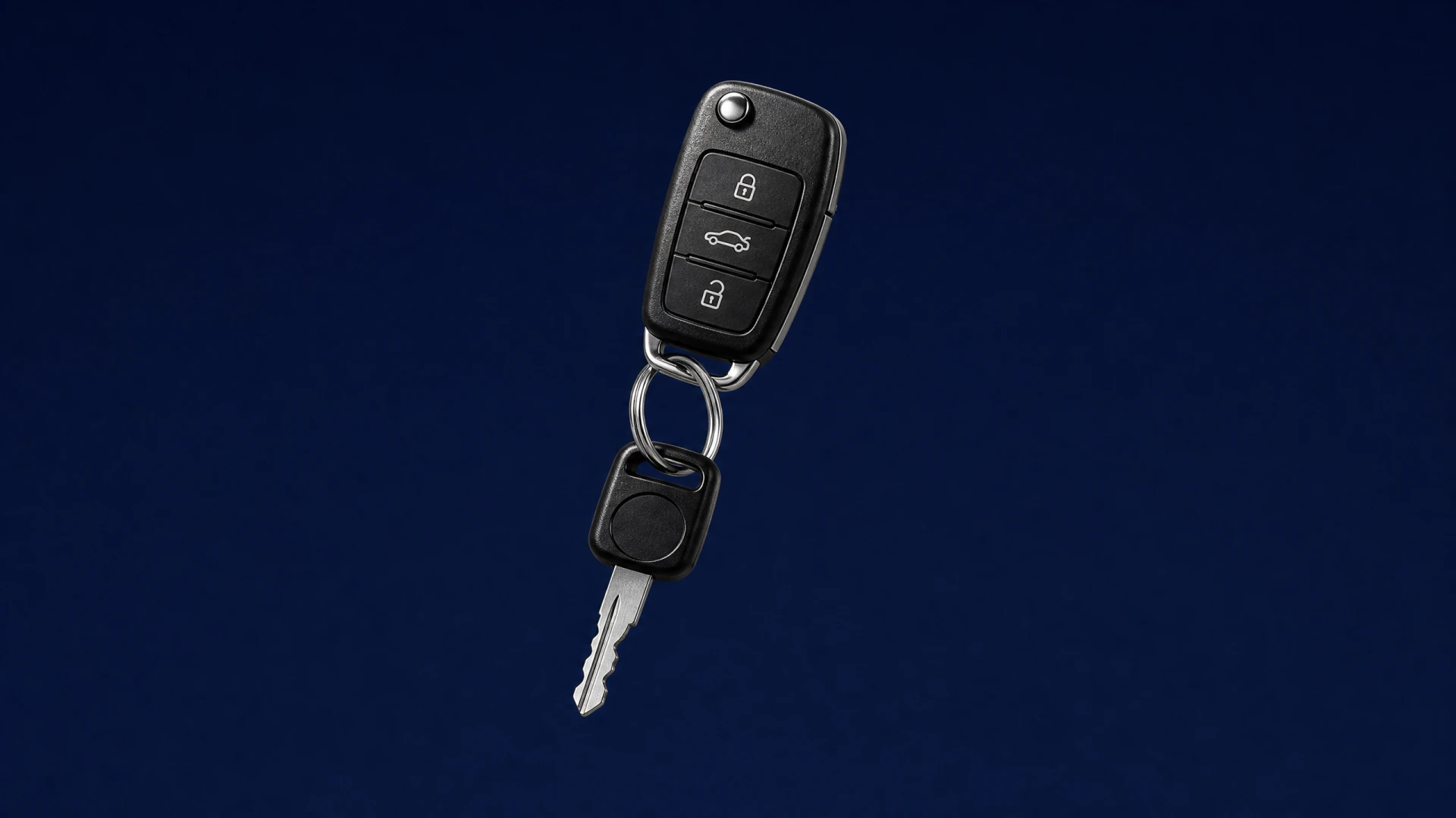 A black flip car key fob attached to a metal ignition key on a silver keyring, photographed against a dark blue background.