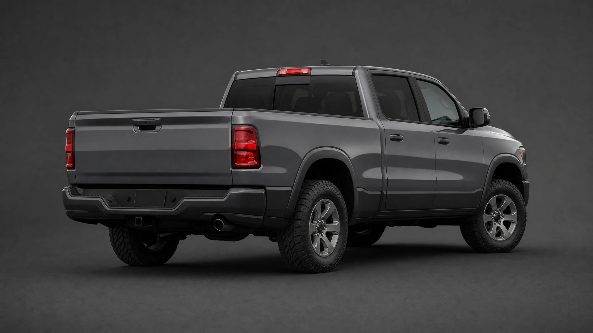 A dark gray full-size crew cab pickup truck with all-terrain tires, photographed from the rear three-quarter angle in a studio setting.