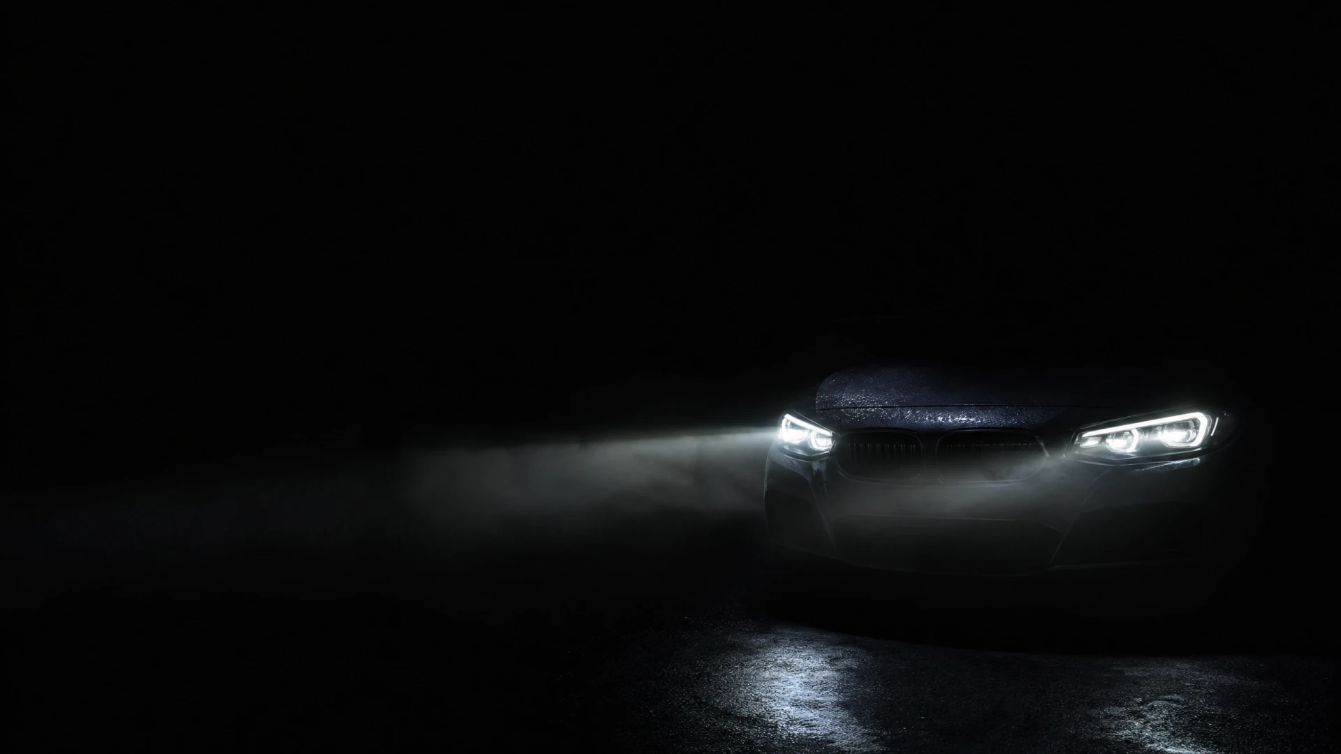 A dark sedan faces the camera in near-total darkness, its two bright headlights cutting through ground-level fog.