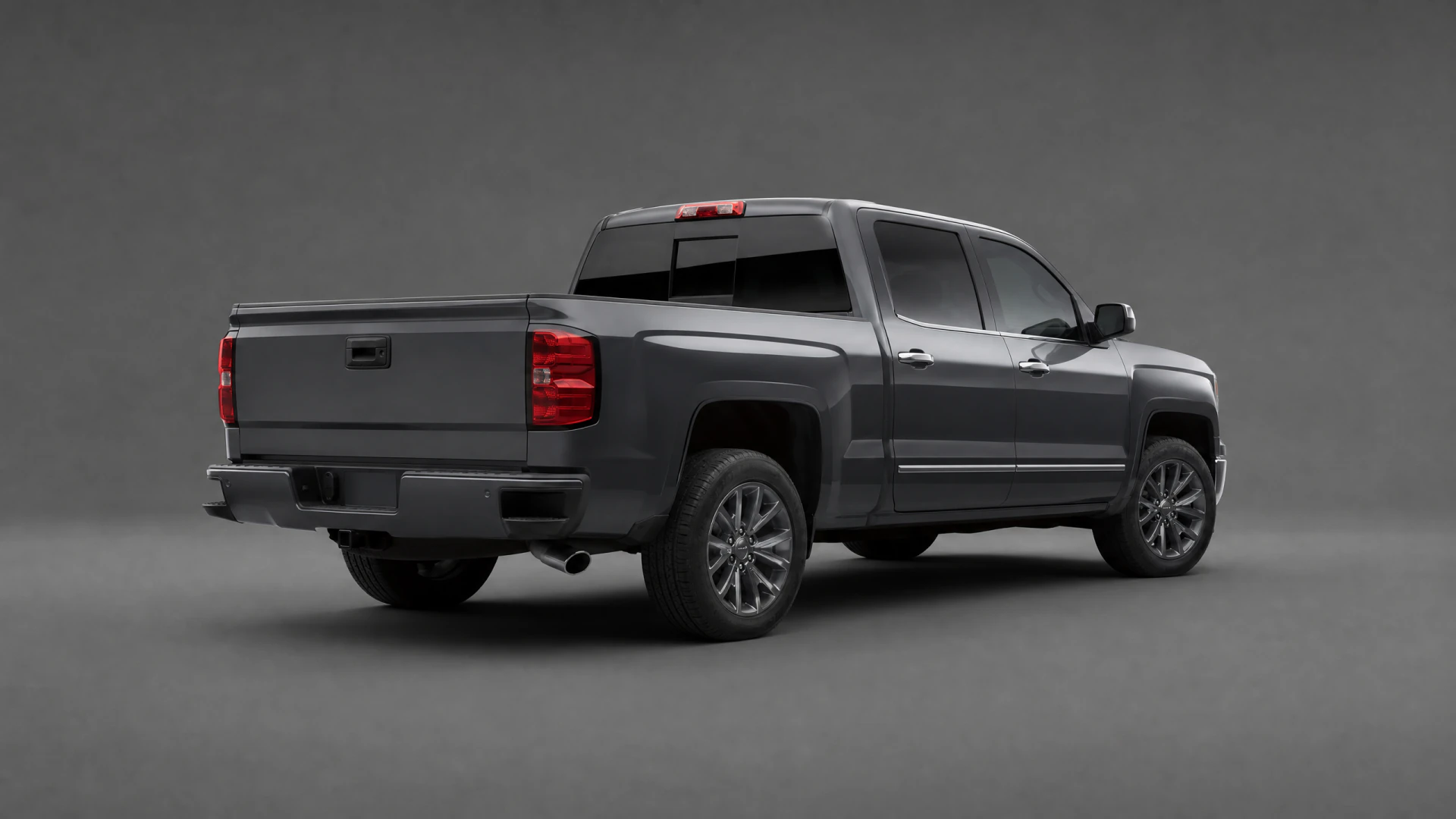 A dark gray crew cab pickup truck photographed from the rear three-quarter angle in a studio setting.