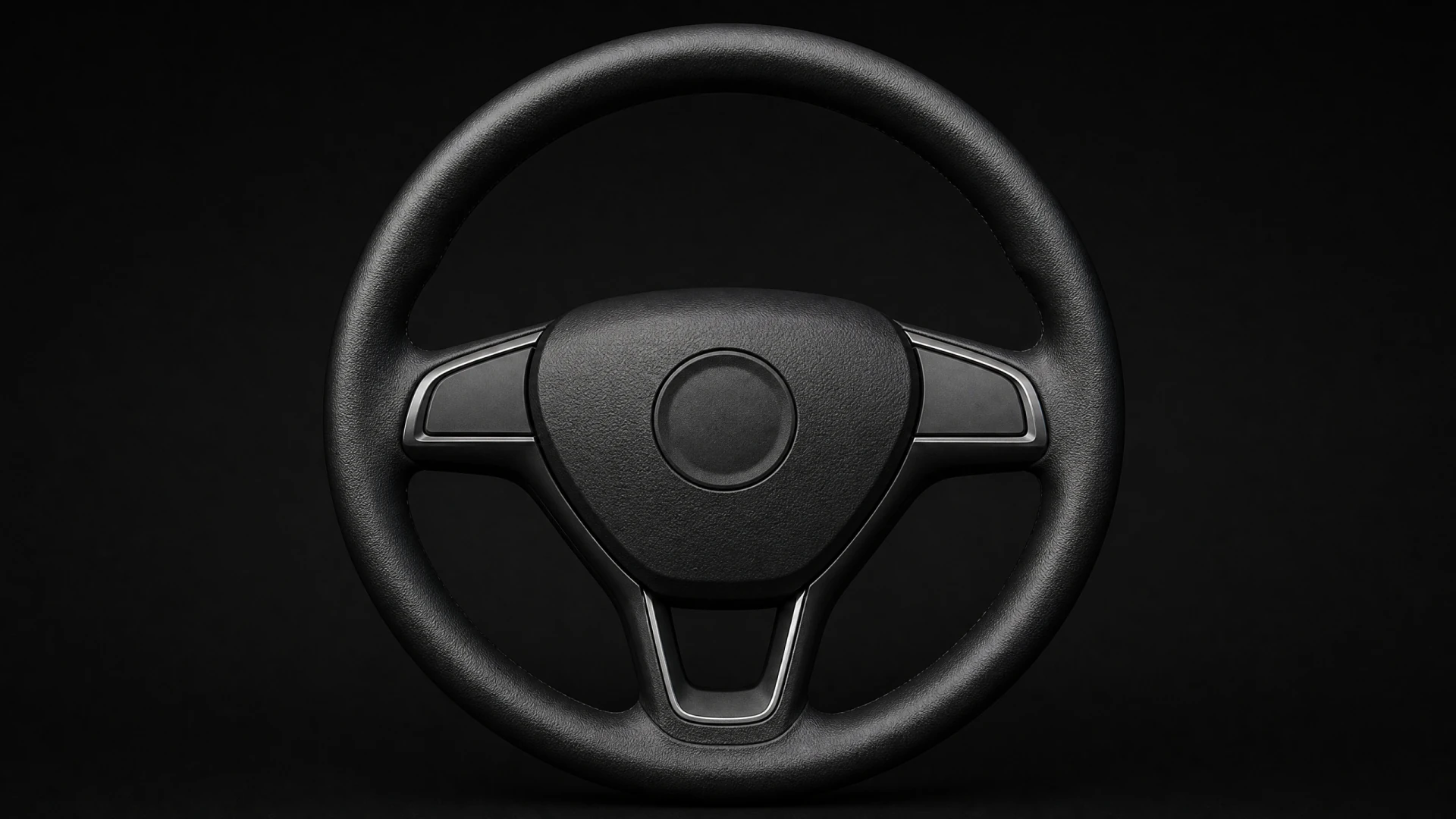 A black leather three-spoke car steering wheel with integrated controls, photographed against a black background.