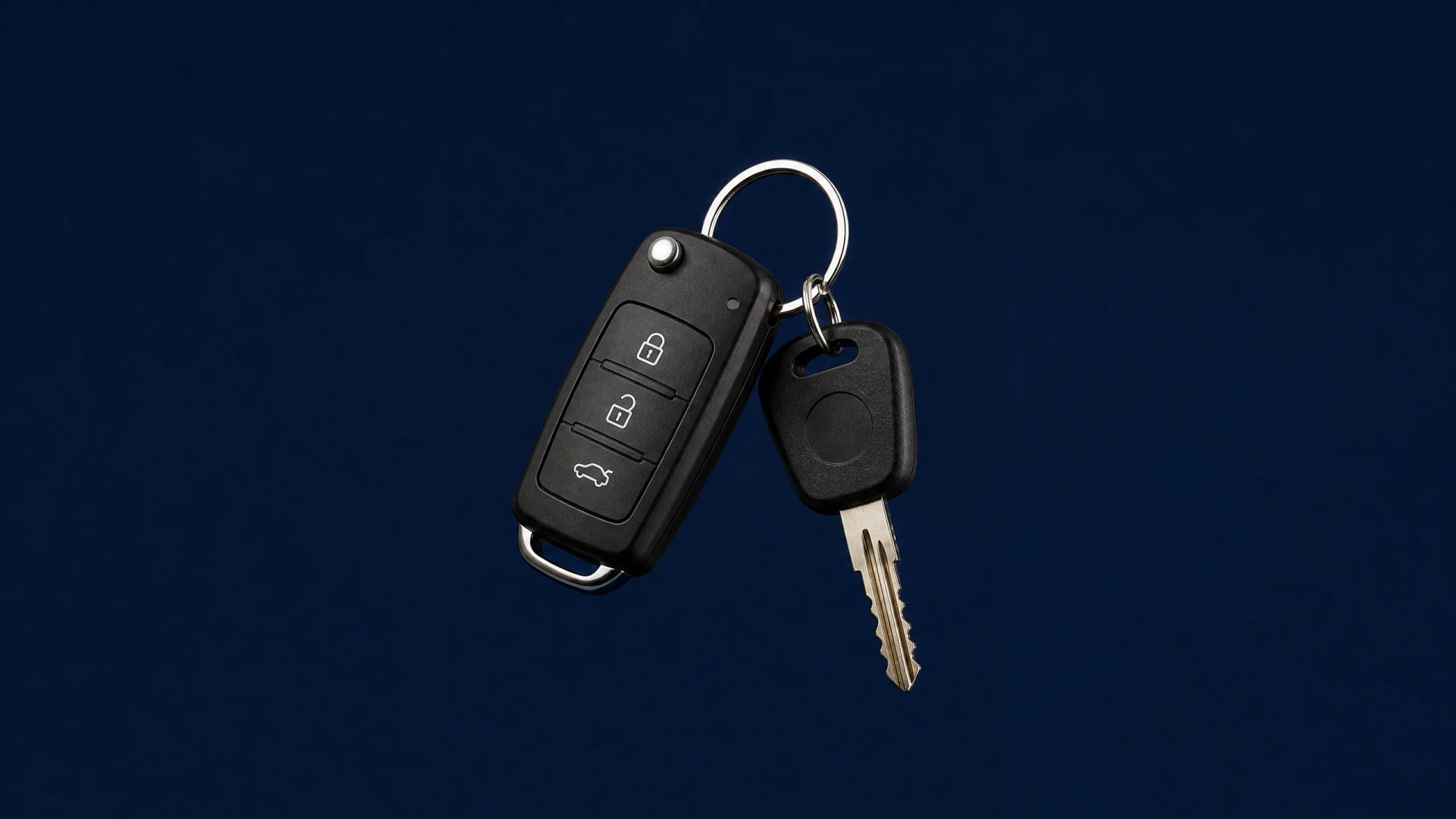 A black flip car key fob with three buttons attached by a metal ring to a separate brass key.