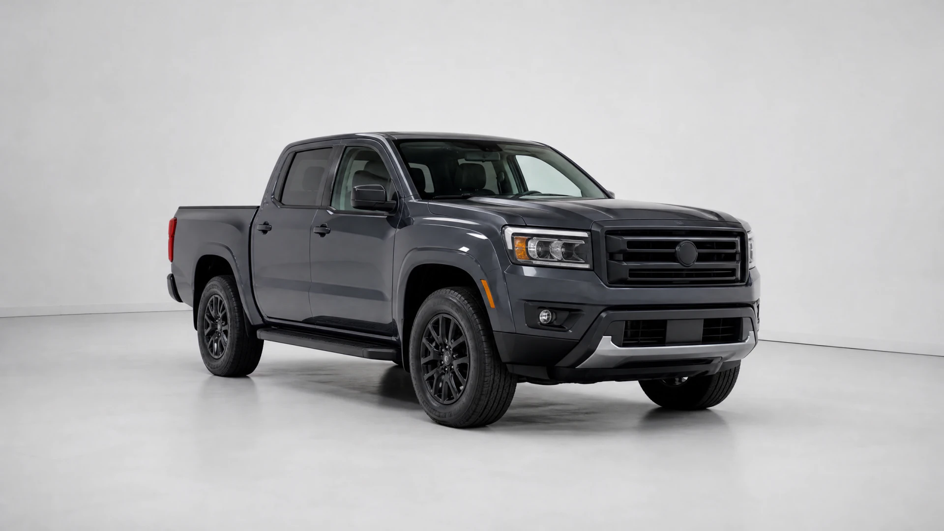 A dark gray crew-cab pickup truck with black alloy wheels and a blacked-out grille, photographed in a studio setting.
