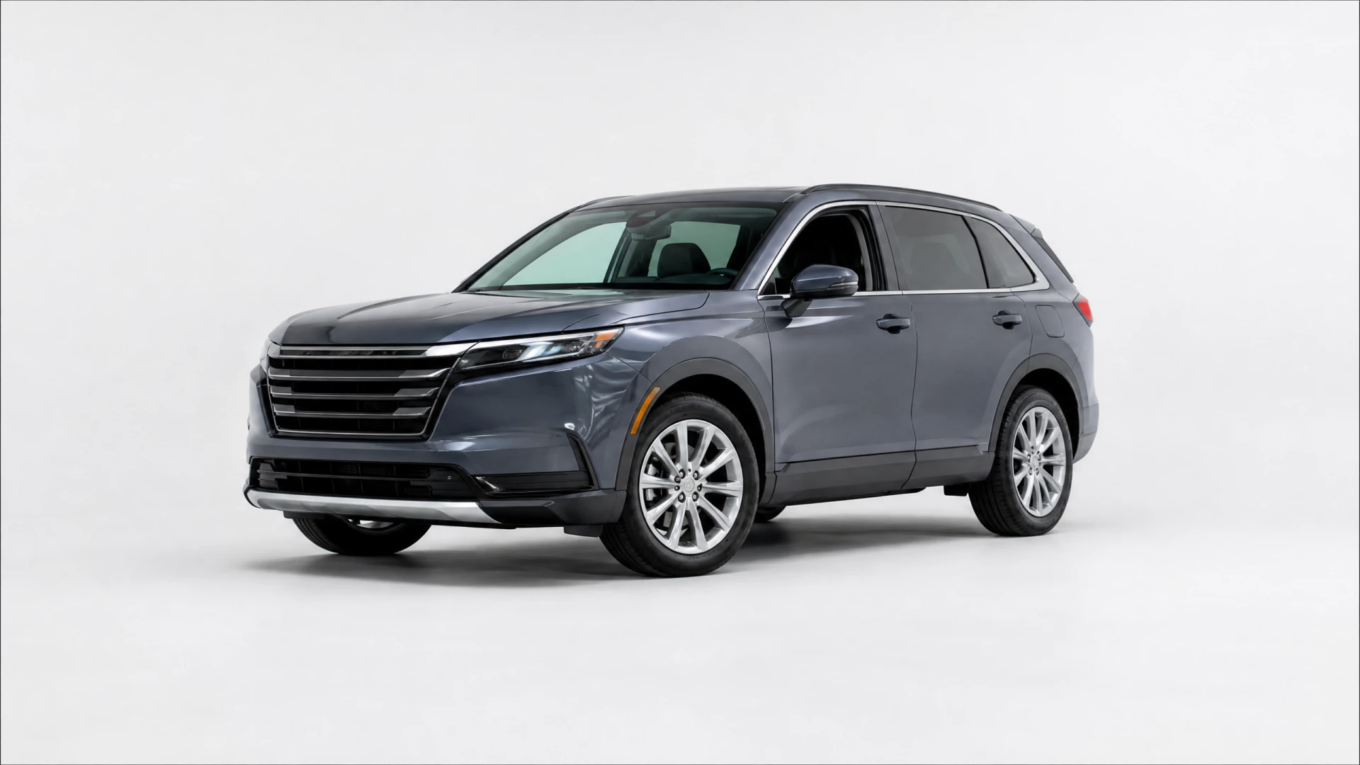 A dark gray three-row SUV photographed in a white studio setting, showing its front grille, headlights, and alloy wheels.