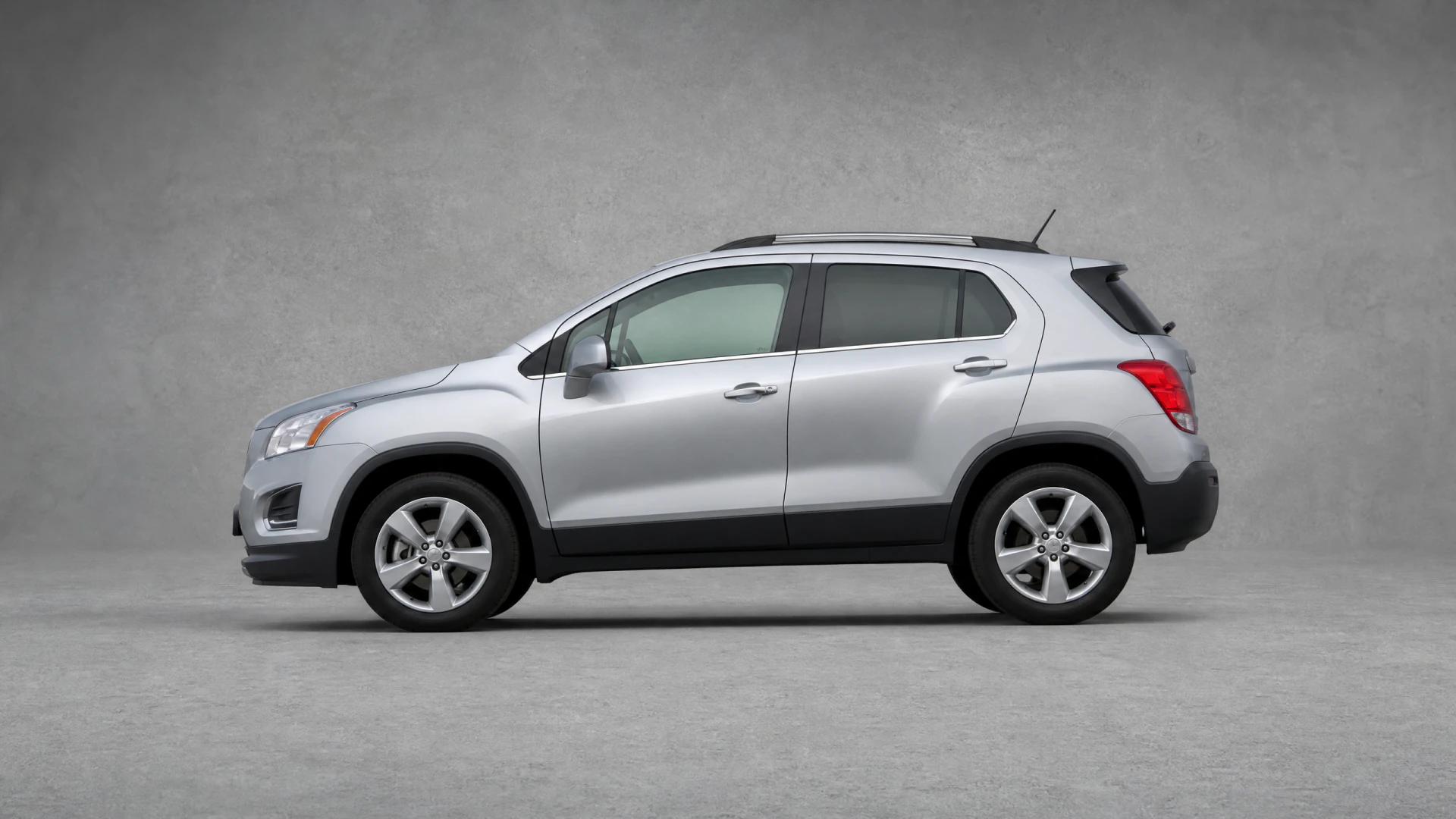 A silver compact SUV photographed in profile view against a neutral gray studio background.