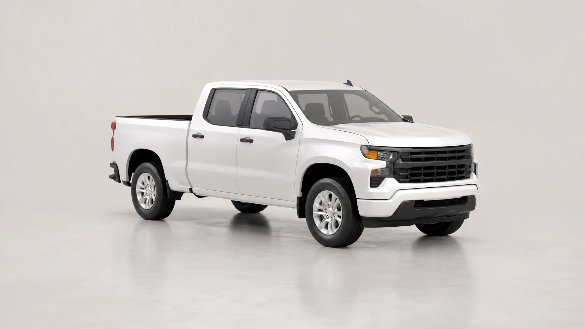 A white double-cab pickup truck with a black grille and silver wheels, photographed in a studio setting.