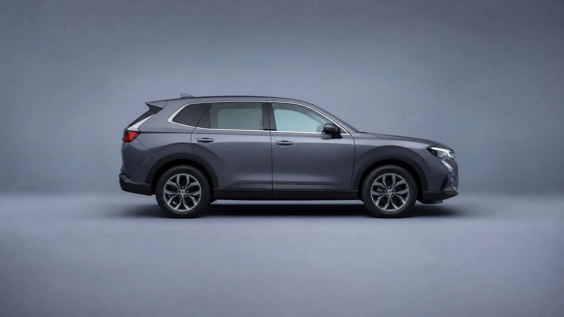 A dark gray SUV photographed from the side in a studio setting against a gray background.