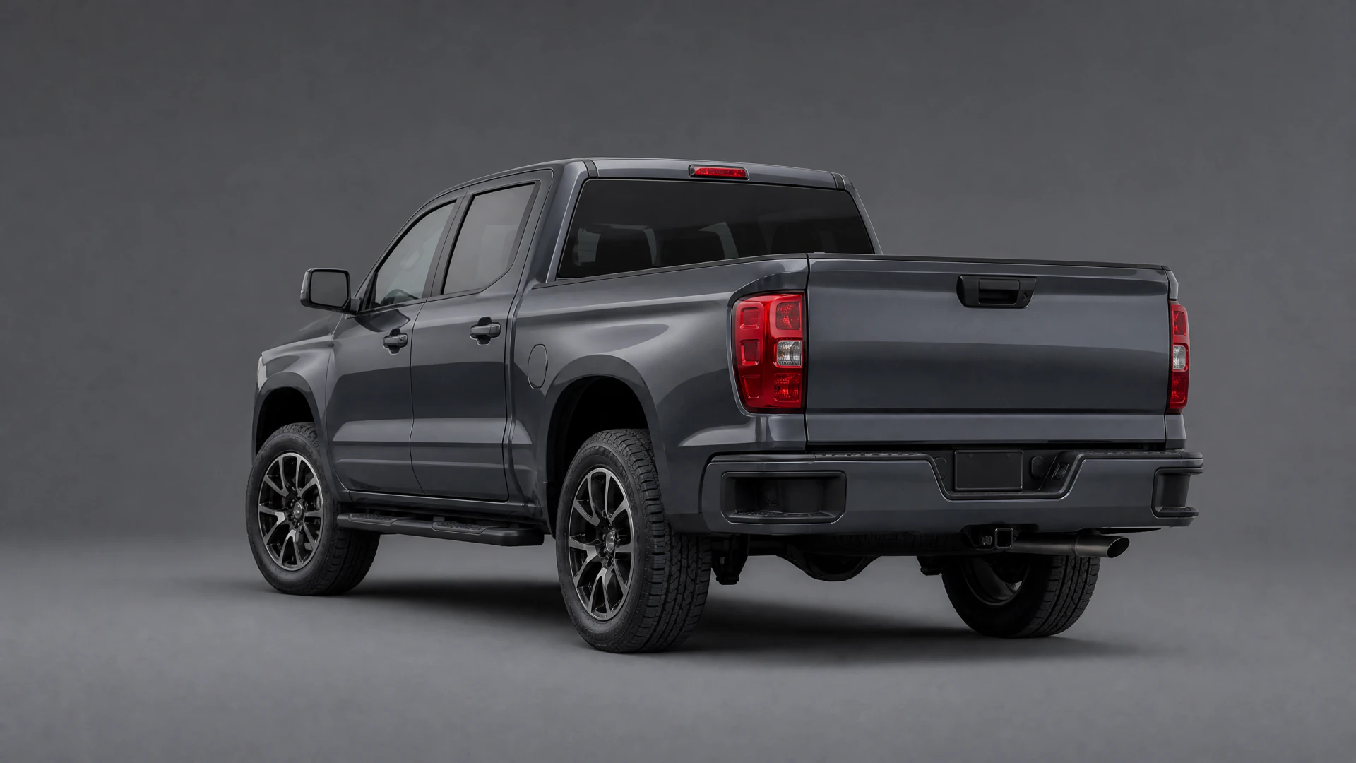 Rear three-quarter view of a dark gray crew-cab pickup truck photographed in a studio setting.