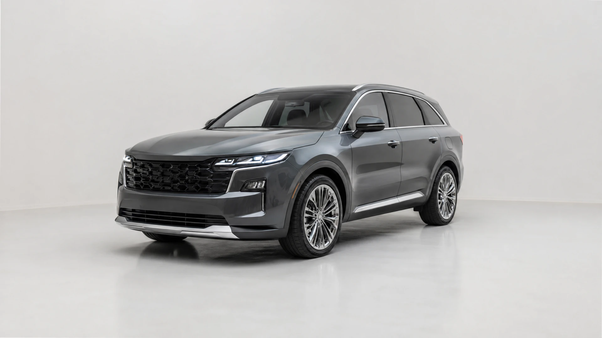 A dark gray three-row SUV with multi-spoke alloy wheels and a mesh grille, photographed from a front three-quarter angle in a white studio.