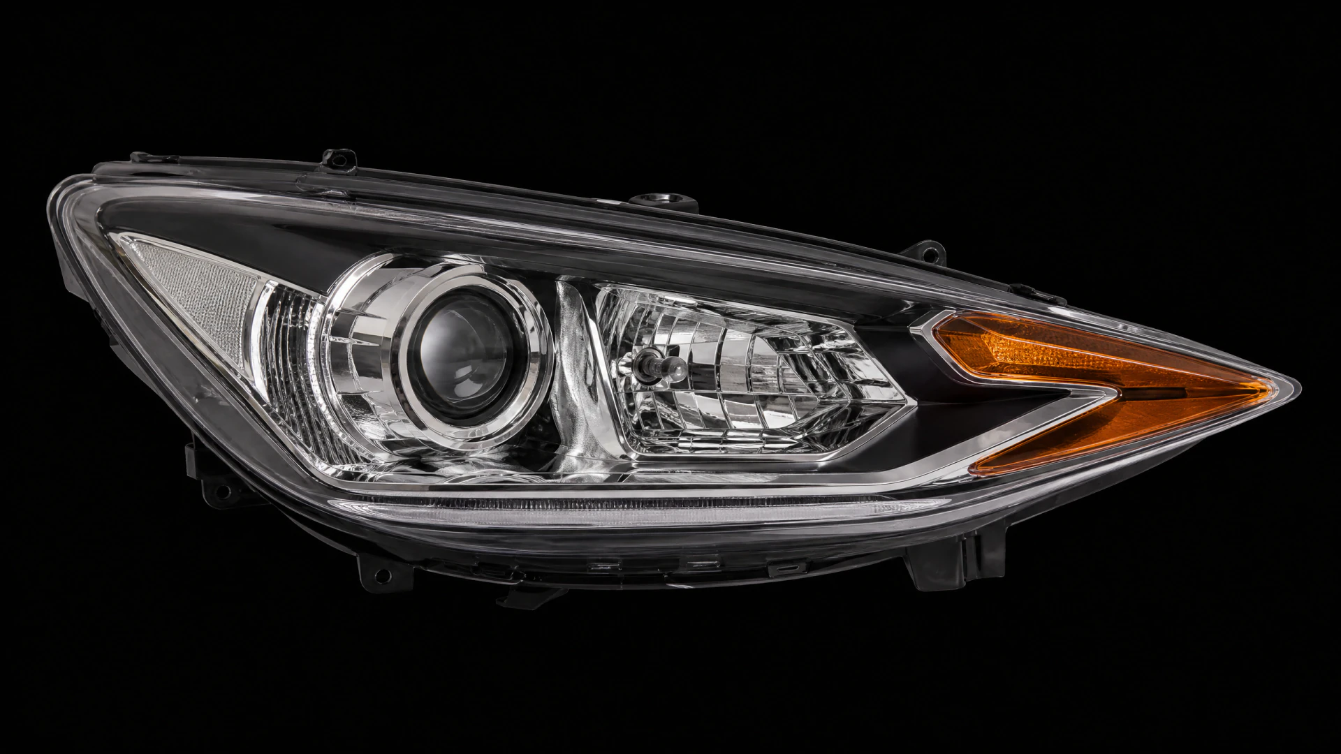 A chrome and black automotive headlight assembly with a projector lens, reflector housing, and amber turn signal, photographed against a black background.
