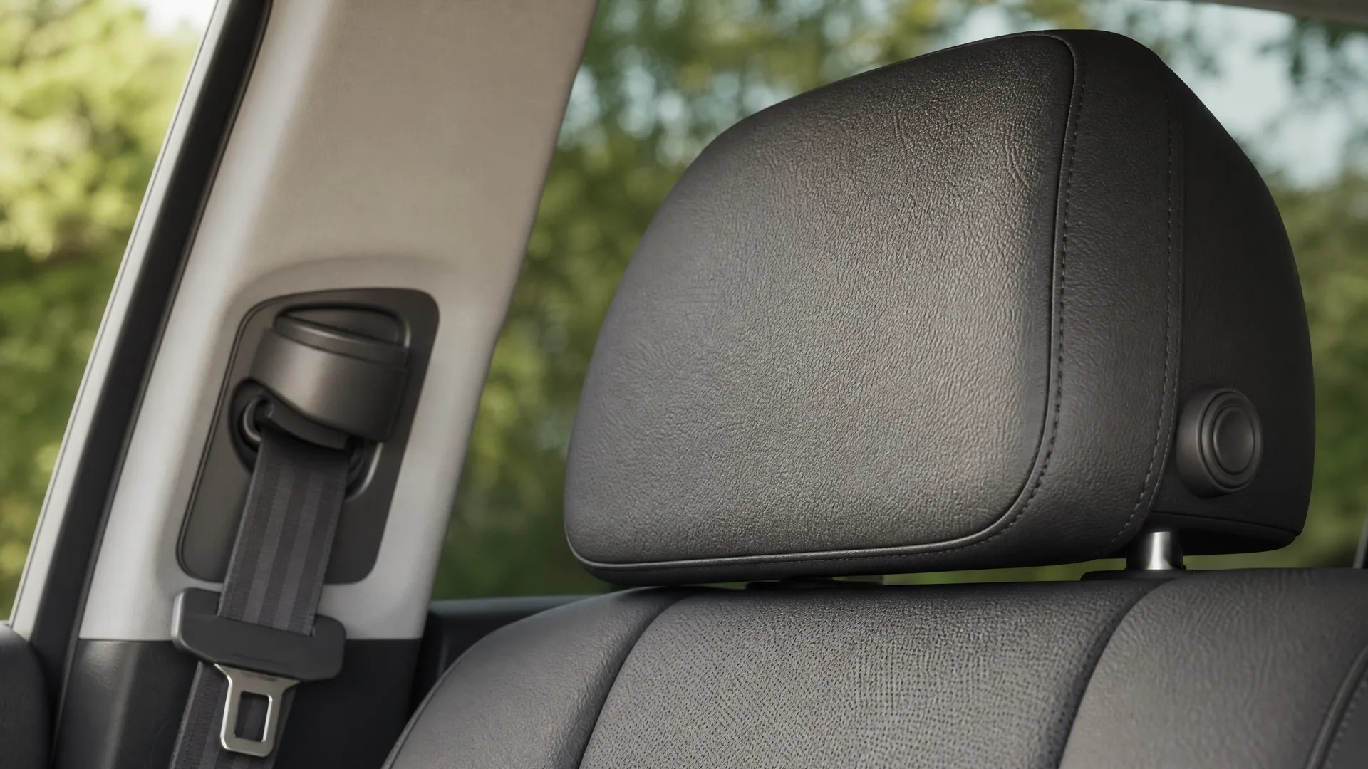 Close-up of a black car seat headrest and front seat back, with a seat belt and B-pillar mount at left and blurred green trees visible through the window.