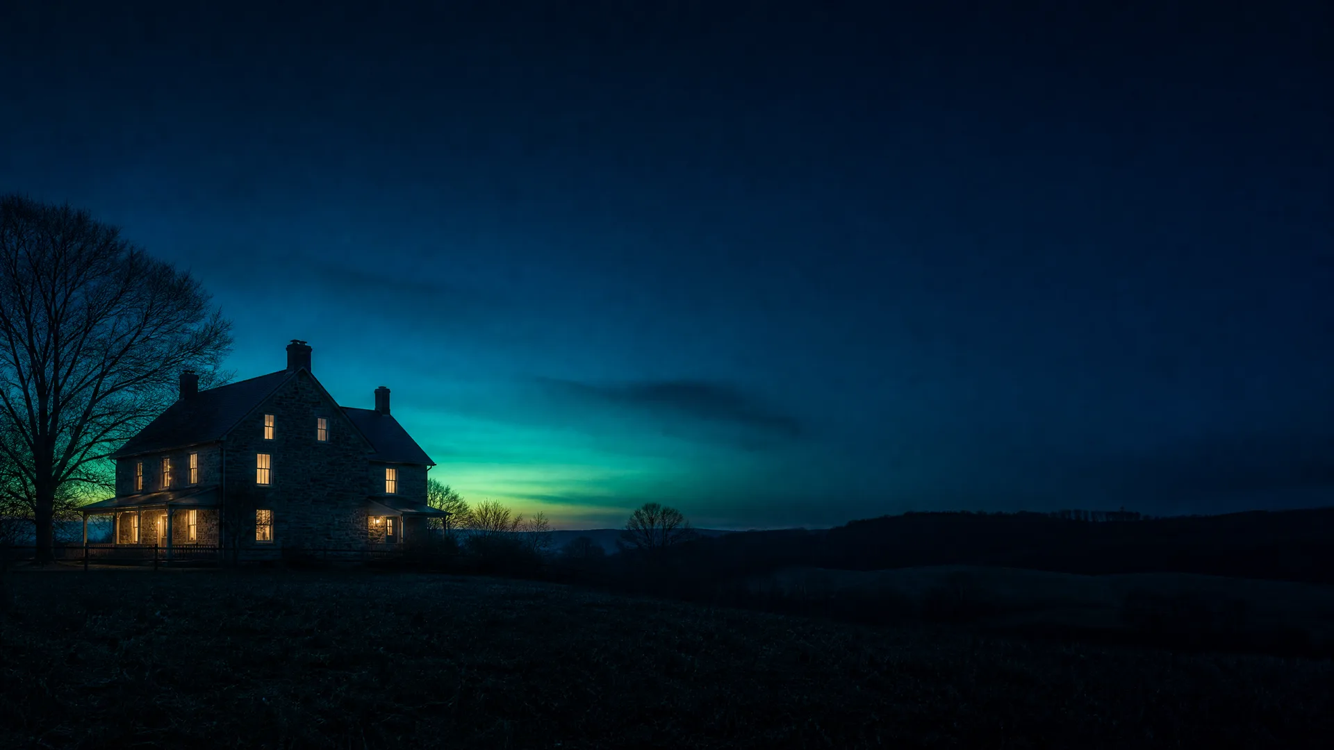 A two-story stone farmhouse with warmly lit windows stands beside a bare tree on a dark field at twilight, under a deep blue sky with a green-yellow glow near the horizon.
