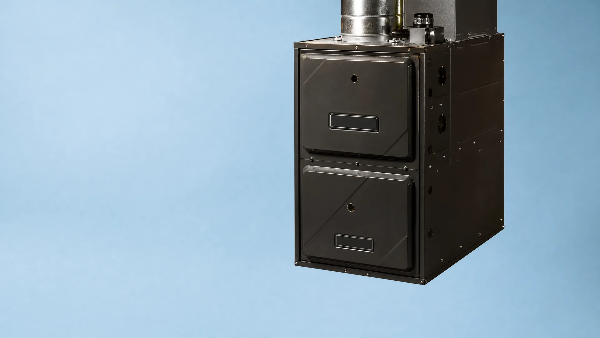 A dark gray residential furnace with two front access panels and a metal flue pipe on top, shown against a plain light blue background.